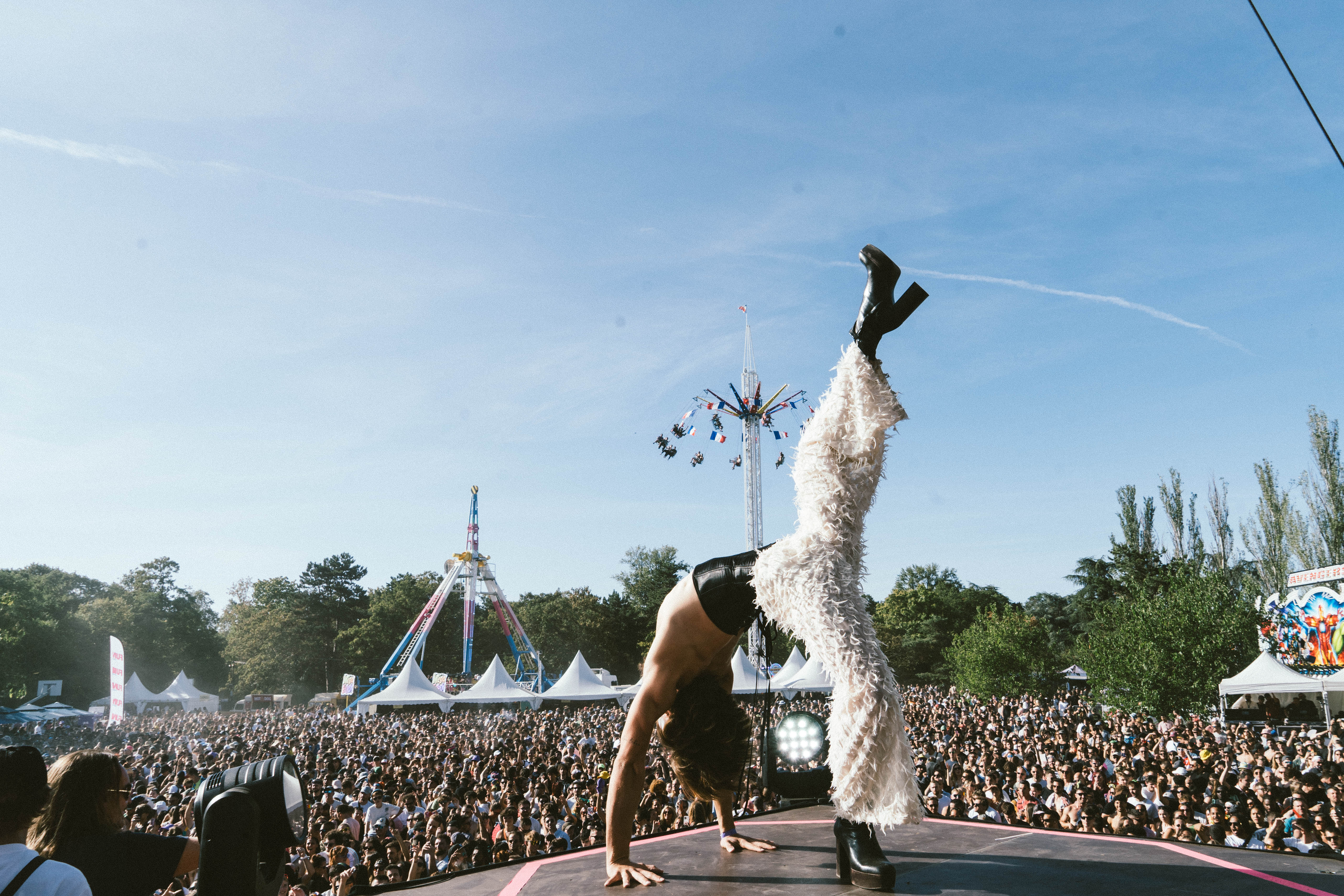 le festival depuis la grande scène avec un premier plan un danseur et en arrière plan les manèges signatures de Madame Loyal.